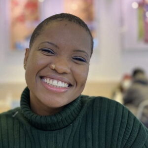Akilah Chatman, smiling, wearing a black striped turtleneck