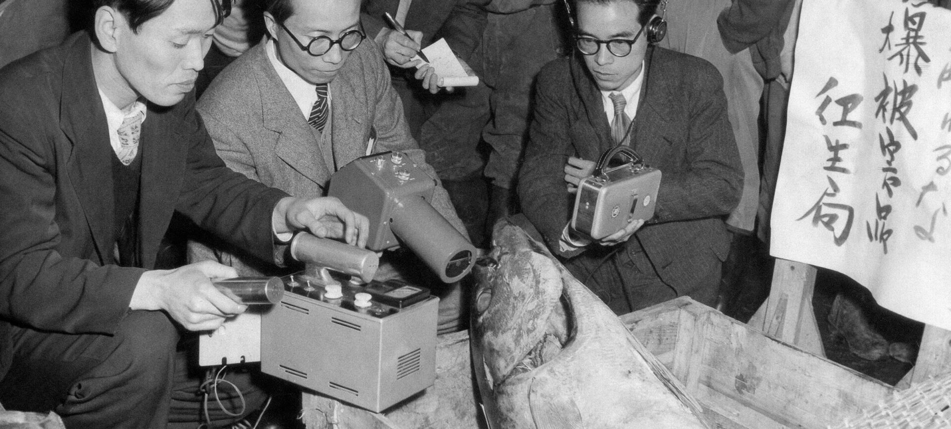 A group of men gathered around a large fish in a crate