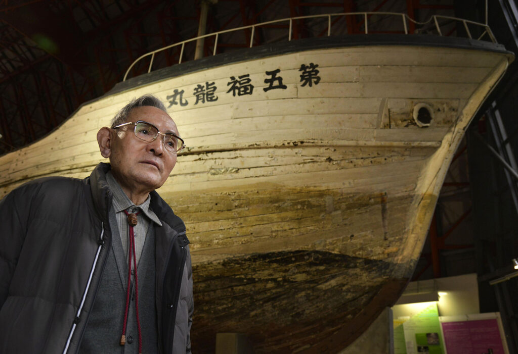 A man standing in front of a boat in a museum