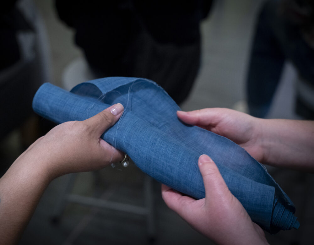 3 hands touching a blue textile