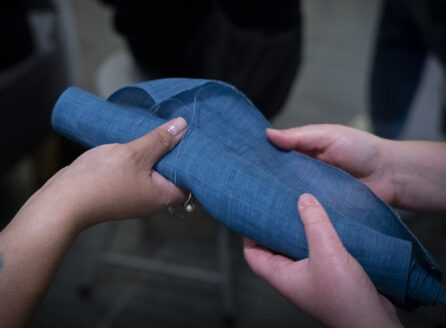 3 hands touching a blue textile