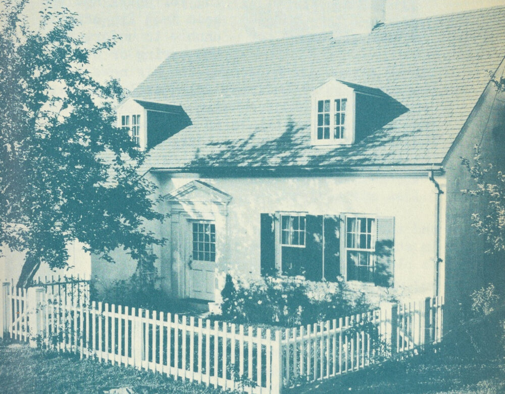 monochrome image of a home with picket fence