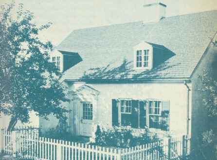 monochrome image of a home with picket fence