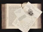 old book with newspaper clipping, wire, and handwritten notes on top of pages