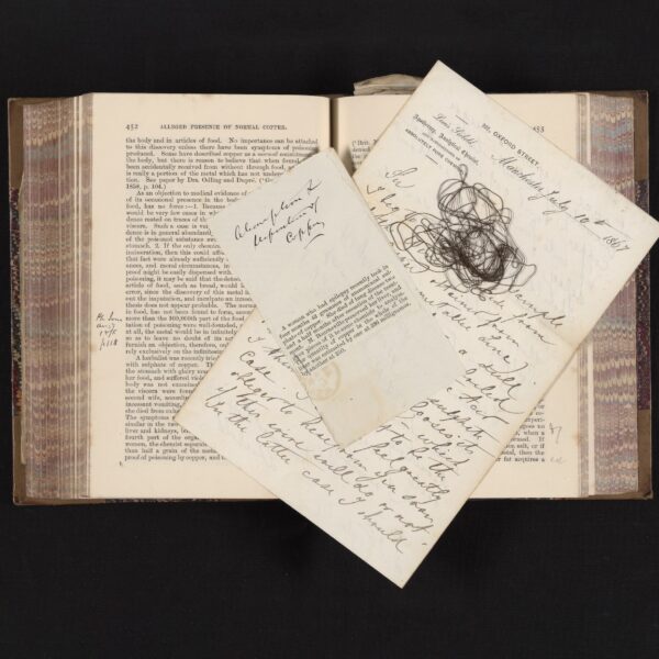old book with newspaper clipping, wire, and handwritten notes on top of pages