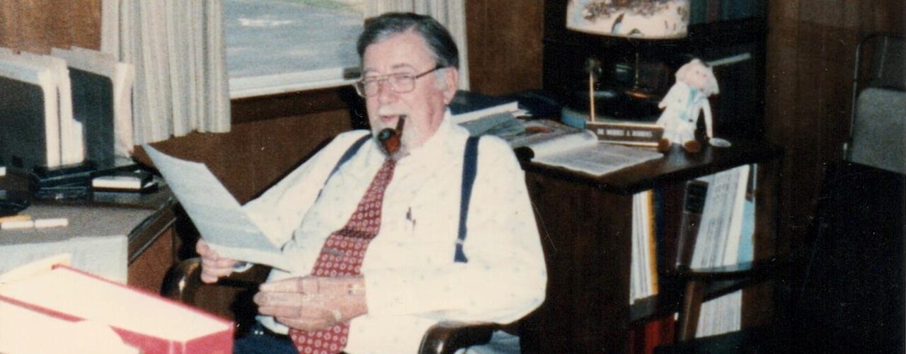 man sitting at a desk smoking a pipe
