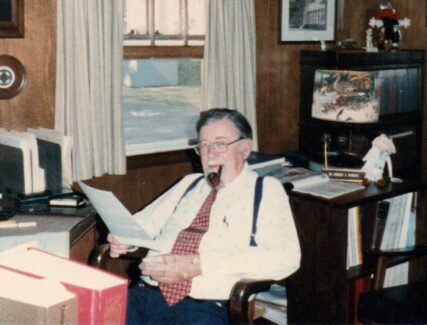 man sitting at a desk smoking a pipe