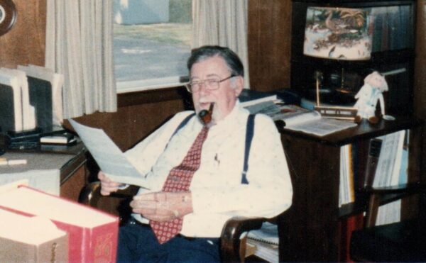 man sitting at a desk smoking a pipe
