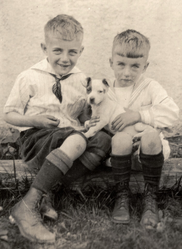 Two boys sitting with a small dog