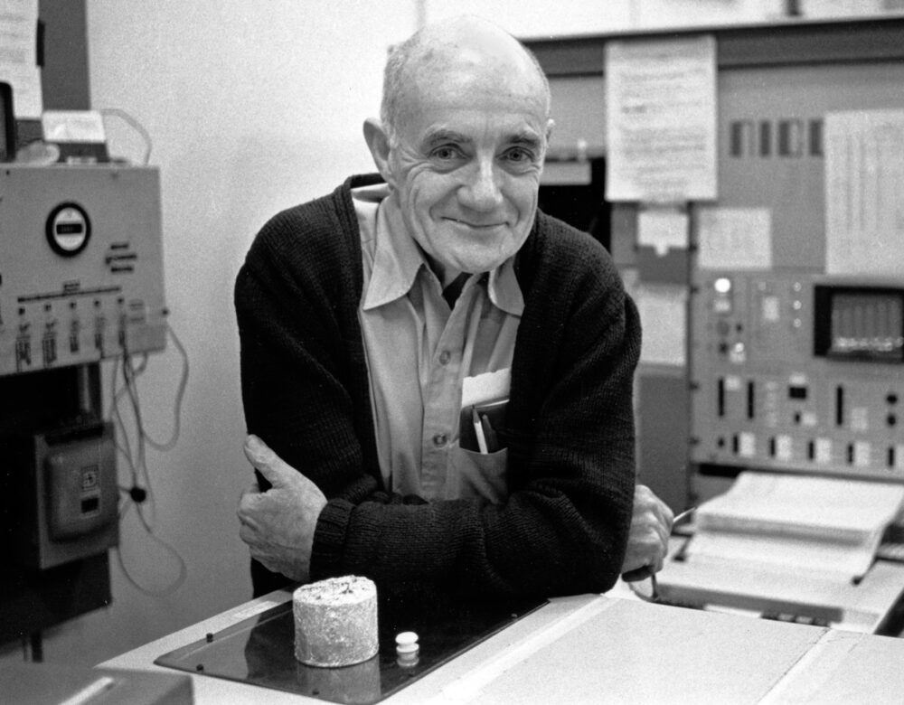 A man leaning on a laboratory bench with machines in the background
