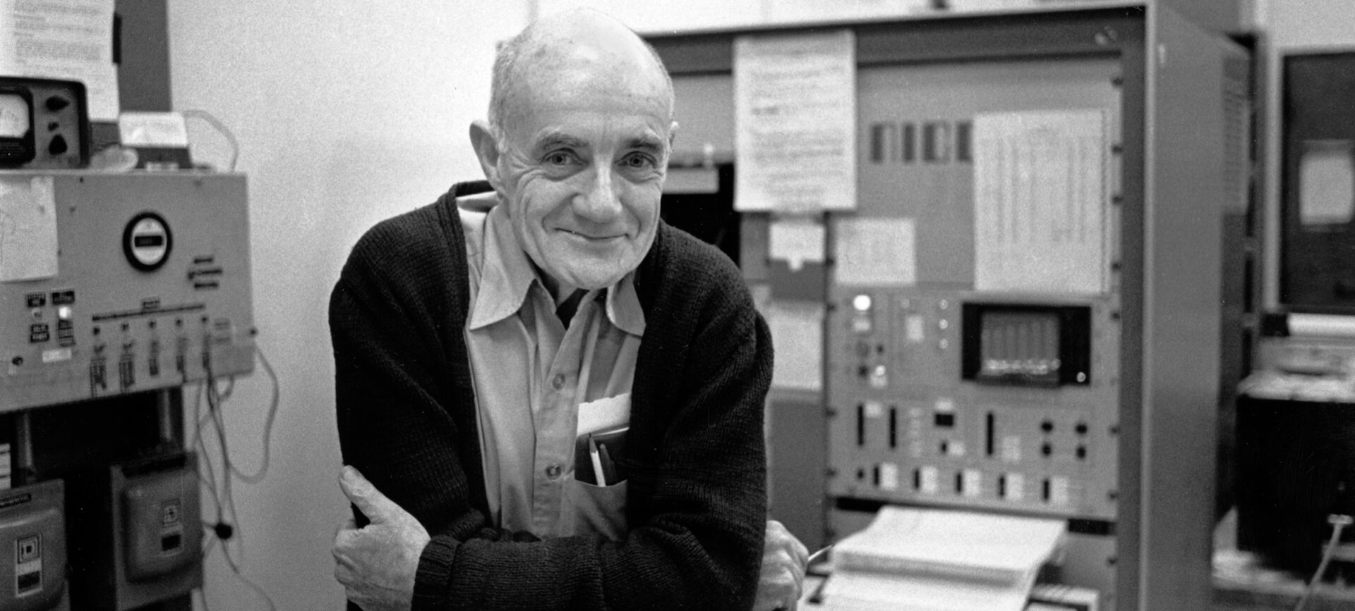 A man leaning on a laboratory bench with machines in the background