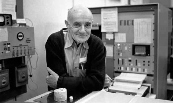 A man leaning on a laboratory bench with machines in the background