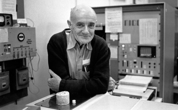 A man leaning on a laboratory bench with machines in the background