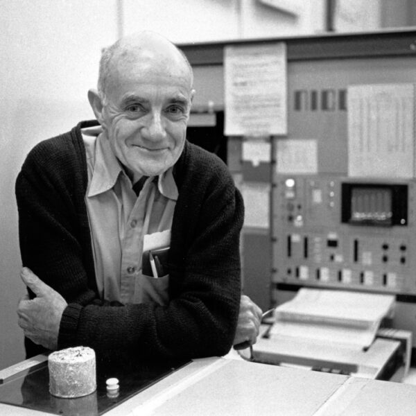 A man leaning on a laboratory bench with machines in the background