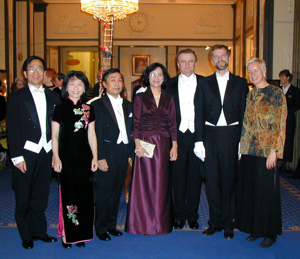 A group of seven people in formal attire posing for a photograph