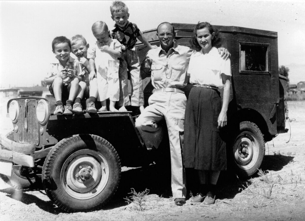 A man, woman, and four children posing next to a Jeep.