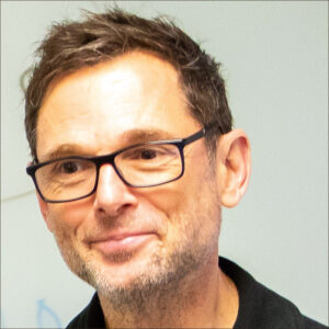 indoor headshot of David Herzberg wearing glasses, head tilted to his right
