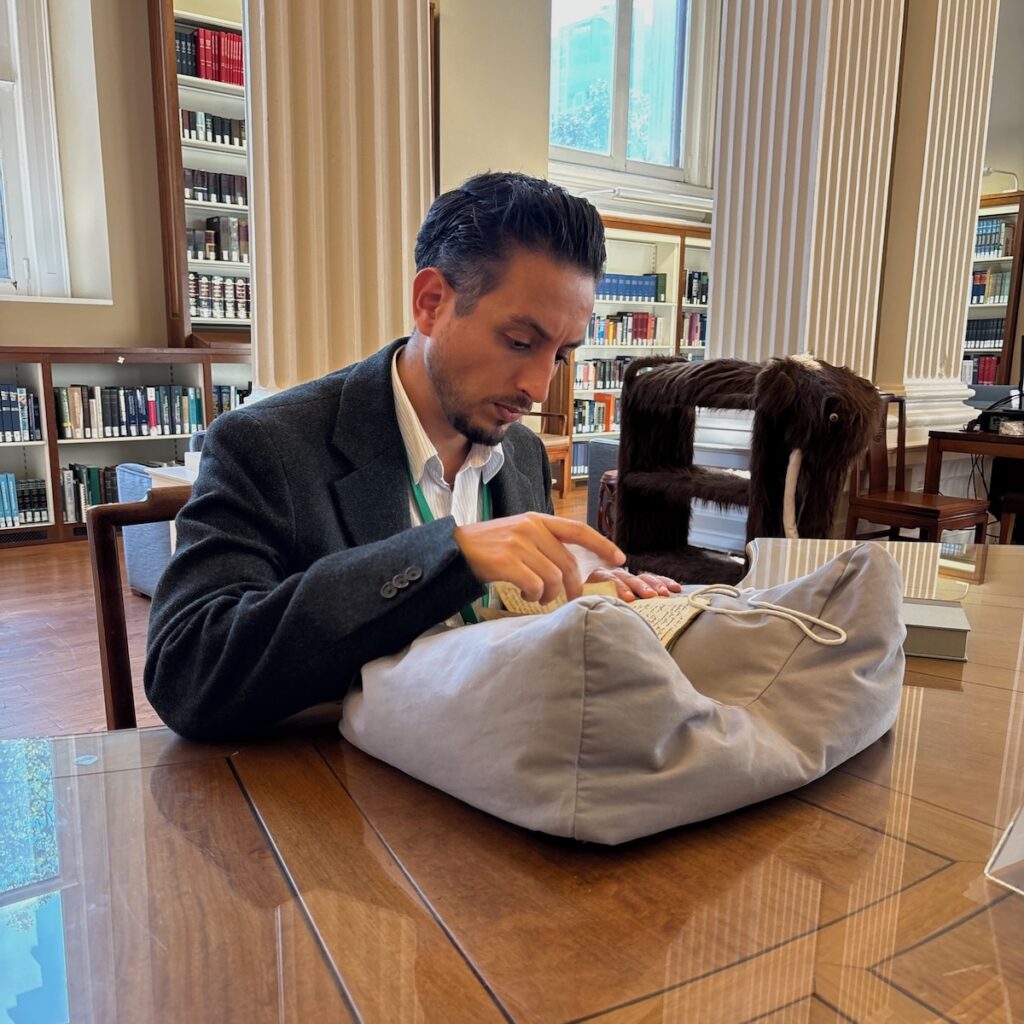 man sitting at a table in a library looking at a book