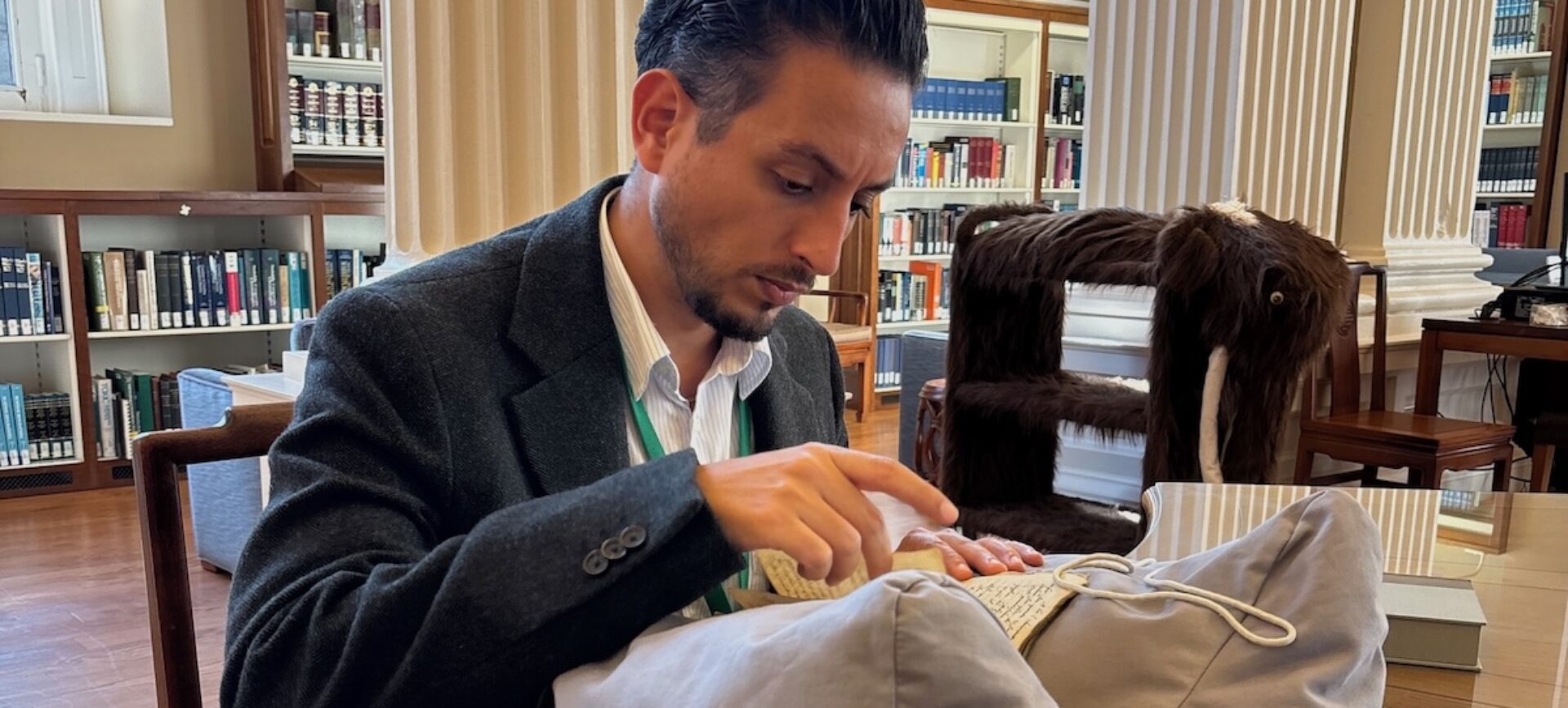 man sitting at a table in a library looking at a book