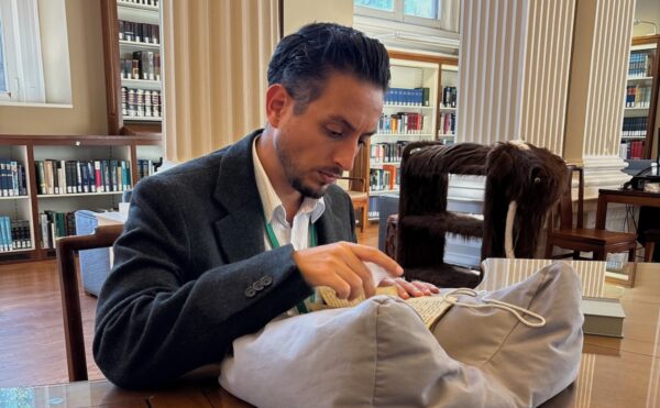 man sitting at a table in a library looking at a book