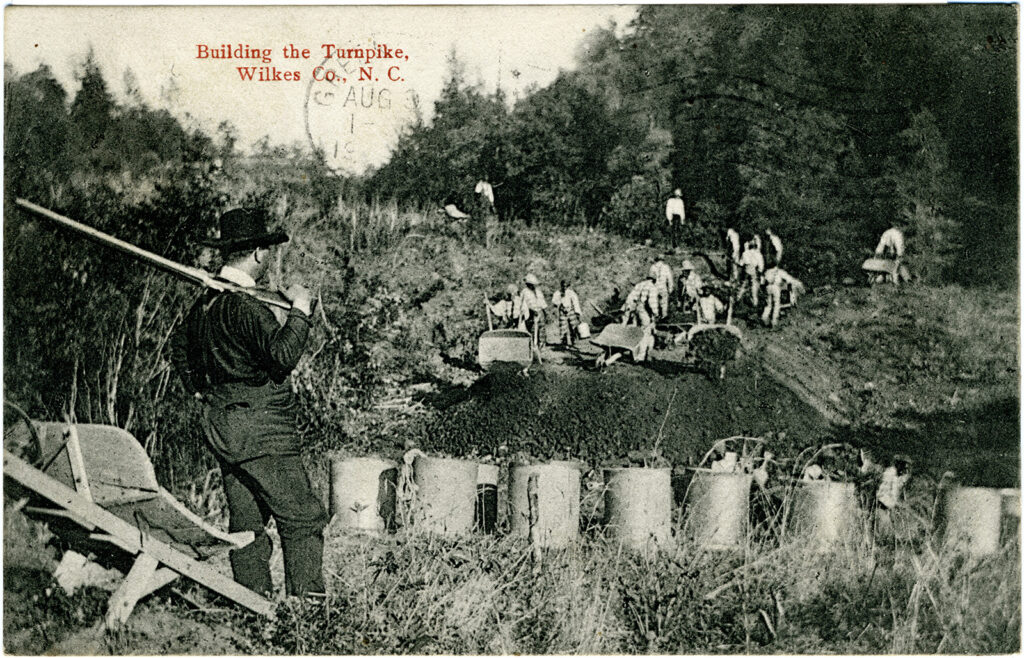 A man with a gun observing a group of men building a road. A label reads, “Building the turnpike, Wilkes Co., N.C.”