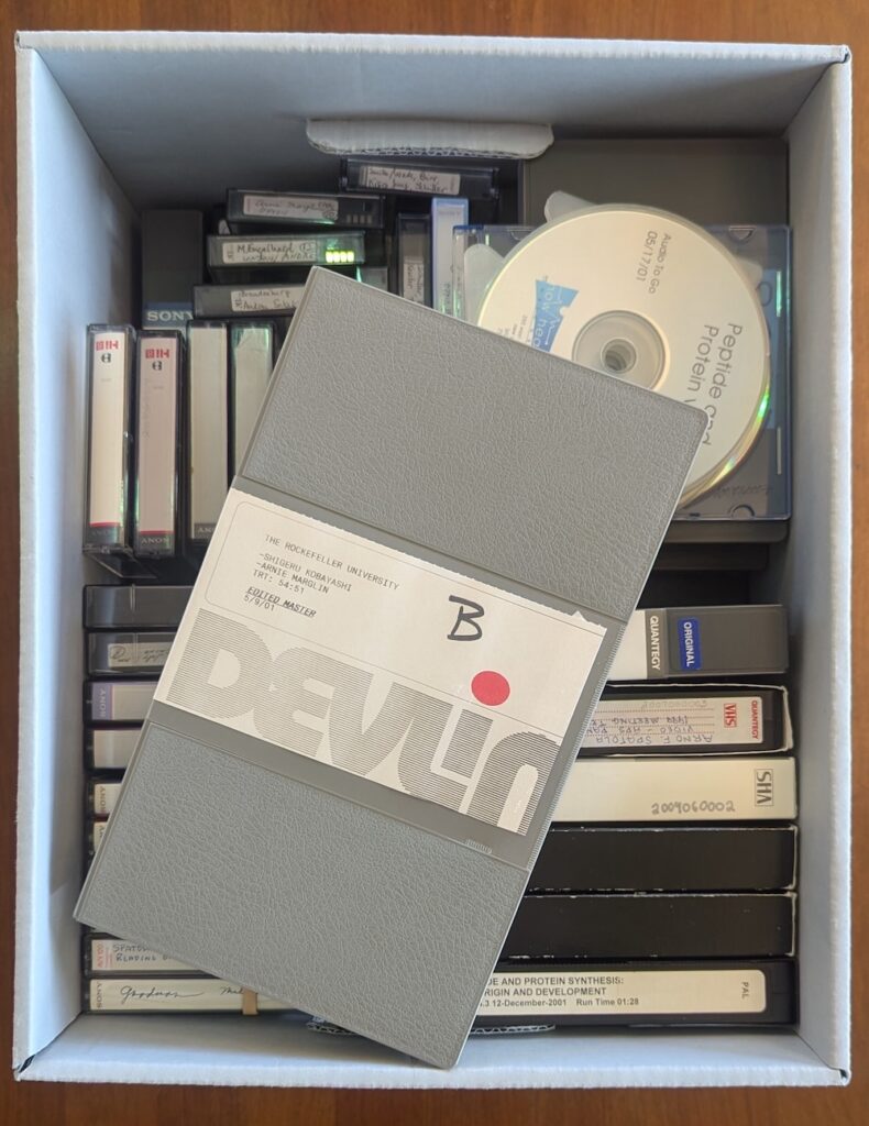 A box of old audiovisual materials including VHS tapes